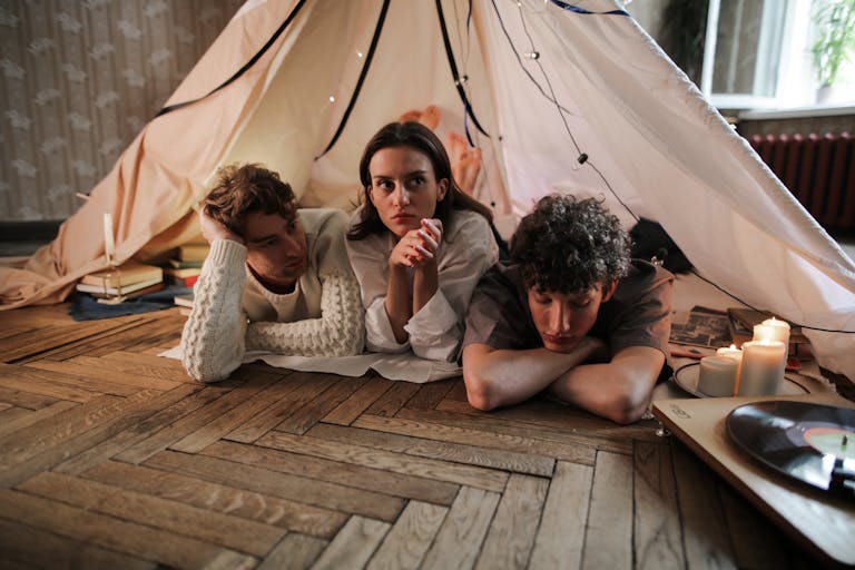 Three young adults relaxing in a cozy indoor tent environment with candles and records.