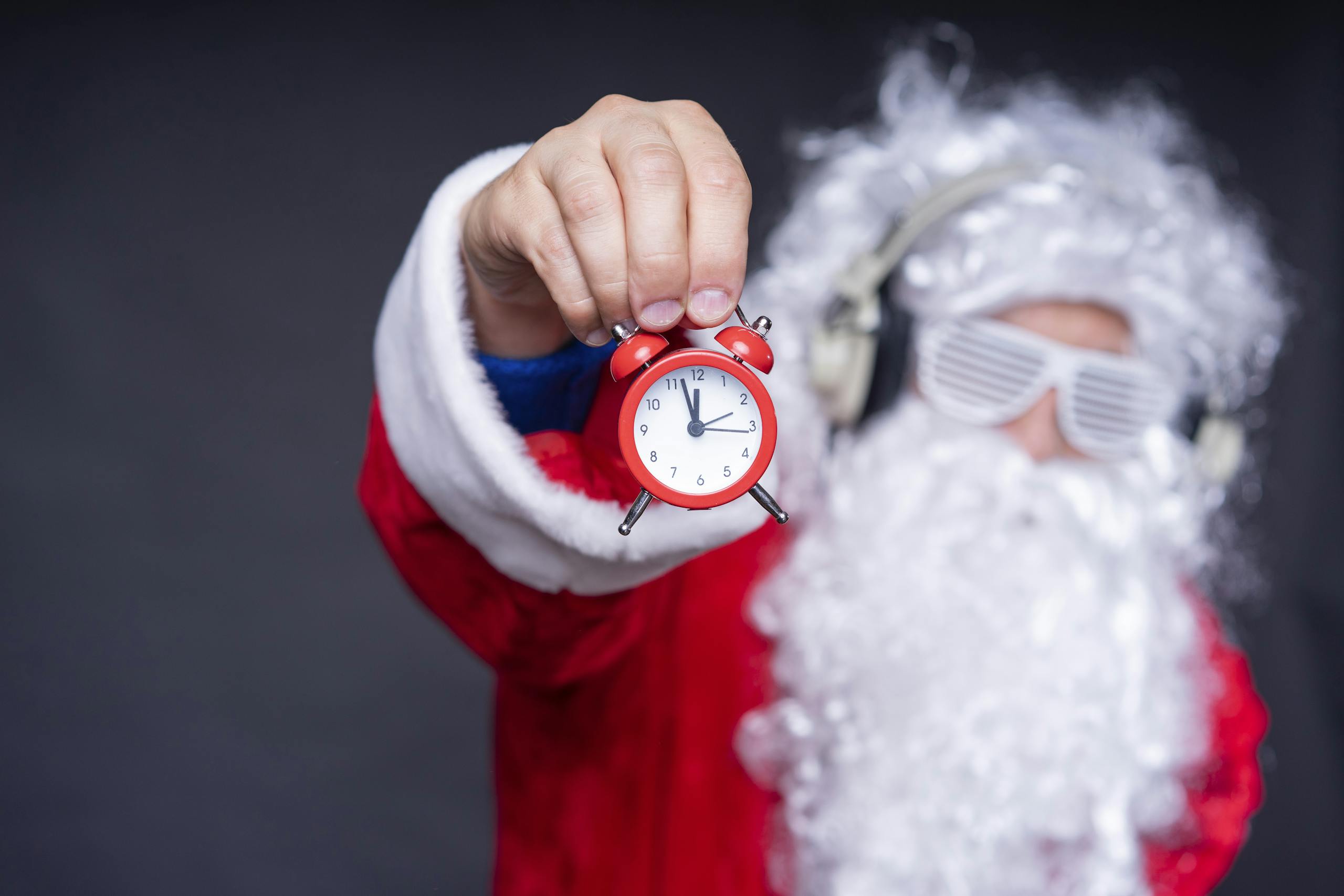 Santa Claus in sunglasses holding an alarm clock, capturing holiday humor and excitement.